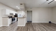 Located at 8120 Mainland Dr in San Antonio, TX 78240, this one-bedroom, one-bathroom residence offers a well-designed single-floor layout that makes efficient use of its space throughout. The interior features wood-look plank flooring in the main living areas, complemented by neutral warm-gray walls and white trim that give the home a clean, modern aesthetic.

The open-concept living and dining area is bright and airy, with a ceiling fan overhead and sliding glass doors that lead directly to a private patio, allowing natural light to fill the space. The kitchen is a functional galley-style layout appointed with white cabinetry, dark granite-style countertops, stainless steel appliances including a dishwasher and refrigerator, and a peninsula with a built-in sink that opens toward the dining area — ideal for casual interaction between rooms. A dedicated laundry area is conveniently accessible from the kitchen.

The bedroom is generously sized, finished with plush carpet, a ceiling fan, a window for natural light, and access to a walk-in closet. The full bathroom features a single-sink vanity with matching dark countertop, white cabinetry, a large mirror, and a shower-tub combination. Multiple additional closets throughout the unit provide ample storage. The private patio rounds out the home with outdoor living space.
