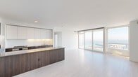 Located at 45 Lansing Street in San Francisco's Rincon Hill neighborhood, this modern 2-bedroom, 2-bathroom residence offers a thoughtfully designed open-concept layout with premium finishes throughout. The combined kitchen and living area serves as the heart of the home, featuring light-toned tile flooring, white walls, and expansive floor-to-ceiling sliding glass doors that frame sweeping views of the San Francisco Bay. The kitchen is appointed with rich dark wood cabinetry, white upper cabinets with under-cabinet lighting, a generous center island with a quartz countertop, and a full suite of stainless steel appliances including a gas range, built-in oven, microwave, and refrigerator. In-unit stacked washer and dryer are also conveniently included. The bedrooms offer plush carpeting and large windows showcasing impressive views of the Bay and the city skyline, including the Bay Bridge. Both bathrooms are elegantly finished with marble-tiled soaking tubs and showers, floating vanities, large mirrors, and warm ambient lighting. The clean, minimalist aesthetic is carried throughout the entire residence, creating a bright and cohesive living environment.