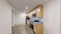 This 500 square foot apartment in Newport News, VA, offers a practical and modern living space. The single-floor layout comprises one bedroom, one bathroom, and a well-equipped kitchen. The primary bedroom, measuring 120 square feet, provides ample space for rest and relaxation.

The bathroom features a clean, white design with a combined bathtub and shower unit, complete with a curved shower rod and a built-in soap dish. A standard toilet and a towel rack complete the functional bathroom setup.

The kitchen is a highlight of the apartment, boasting light wood cabinetry and stainless steel appliances. Granite countertops add a touch of elegance, while the over-range microwave and electric stove offer convenience for meal preparation. A window above the sink allows natural light to brighten the space.

Throughout the apartment, polished granite tile flooring adds durability and a sleek appearance. The walls are painted in a crisp white, creating a bright and airy atmosphere. Recessed lighting in the kitchen and pendant lights in other areas provide ample illumination.

The living areas feature high ceilings and minimalist design, with ample wall space for personalization. A small, high-set window in one room offers additional natural light without compromising privacy.

This compact yet efficiently designed apartment at 2800 Washington Ave combines modern amenities with a practical layout, ideal for those seeking a convenient urban living space.