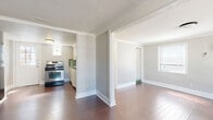 Located at 2613 Crocker St in Houston's vibrant Montrose neighborhood, this single-floor unit offers a well-organized layout comprising a combined kitchen and living room, a full bathroom, and a hallway. Rich, dark hardwood flooring runs throughout the main living areas, lending warmth and character to the space. The living room is bright and open, featuring crown molding, light gray walls, and multiple windows that invite natural light. A wall-mounted mini-split unit provides efficient climate control. The kitchen is functional and thoughtfully laid out, equipped with a stainless steel gas range, a black refrigerator, white cabinetry, and a retro green tile backsplash that adds a charming vintage touch. A stained-glass accent window above the back door brings in additional light and visual interest. The bathroom continues the vintage aesthetic with green diamond-patterned tile flooring, white subway-style wall tiles, a single vanity with white cabinetry, and a combination tub and shower. Crown molding is carried throughout, providing a cohesive architectural detail across the unit. The textured ceilings add to the classic character of this compact yet efficiently designed Houston residence.