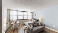 This thoughtfully designed studio unit offers an efficient and comfortable single-floor layout that maximizes every square foot. The open-concept main living area seamlessly integrates the sleeping, lounging, and dining zones, all unified by warm hardwood-style flooring and soft, neutral wall tones. Large windows dressed with sheer curtains and horizontal blinds flood the space with natural light while framing sweeping city views, creating an airy and inviting atmosphere. A textured ceiling adds subtle architectural character throughout.

The galley-style kitchen is well-equipped, featuring white cabinetry, granite countertops, a gas range, a refrigerator, and a stainless steel sink — offering ample storage and prep space within a compact, functional footprint. A louvered closet near the entry provides additional storage convenience.

The full bathroom is finished with warm tile walls, mosaic tile flooring, a granite-topped white vanity, a large mirror, and a shower-tub combination — delivering a clean and polished aesthetic. A rich, dark-wood wardrobe armoire with a mirrored door serves as an elegant and practical storage solution within the main living space. Overall, the unit presents a bright, cohesive, and functional living environment well-suited for efficient urban living.