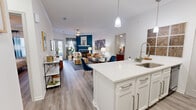 This thoughtfully designed single-floor model unit on Stonecrest Drive in Birmingham, Alabama offers a seamless blend of modern style and functional living. The open-concept layout connects the kitchen, dining, and living areas, creating a bright and airy atmosphere enhanced by wood-look flooring throughout. The kitchen is a standout feature, boasting white shaker cabinetry, quartz countertops, a mosaic tile backsplash, pendant lighting, and a large center island with bar seating — ideal for both meal prep and casual dining. Black appliances, including a refrigerator, range, and microwave, add a bold contrast to the crisp white palette. The living room is anchored by a tiled fireplace set against a striking teal accent wall, with French doors that invite natural light and provide outdoor access. The bedroom is a comfortable retreat with ample natural light from a large window, hardwood-style flooring, and a ceiling fan. Two bathrooms serve the unit — a full bath with a white vanity, quartz countertop, and a tub/shower combination, and a secondary bath equally clean in design. Crown molding and consistent finishes tie the entire space together, conveying a polished, move-in-ready aesthetic.