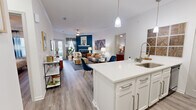 This thoughtfully designed single-floor model unit on Stonecrest Drive in Birmingham, Alabama offers a seamless blend of modern style and functional living. The open-concept layout connects the kitchen, dining, and living areas, creating a bright and airy atmosphere enhanced by wood-look flooring throughout. The kitchen is a standout feature, boasting white shaker cabinetry, quartz countertops, a mosaic tile backsplash, pendant lighting, and a large center island with bar seating — ideal for both meal prep and casual dining. Black appliances, including a refrigerator, range, and microwave, add a bold contrast to the crisp white palette. The living room is anchored by a tiled fireplace set against a striking teal accent wall, with French doors that invite natural light and provide outdoor access. The bedroom is a comfortable retreat with ample natural light from a large window, hardwood-style flooring, and a ceiling fan. Two bathrooms serve the unit — a full bath with a white vanity, quartz countertop, and a tub/shower combination, and a secondary bath equally clean in design. Crown molding and consistent finishes tie the entire space together, conveying a polished, move-in-ready aesthetic.