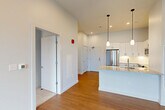 This well-appointed one-bedroom, one-bathroom residence in Natick, MA offers a thoughtfully designed layout with modern finishes throughout. The open-concept living, dining, and kitchen area serves as the heart of the home, featuring warm hardwood-style flooring, soaring ceilings, and recessed lighting that create a bright and airy atmosphere. A large window in the living area allows natural light to flow in and provides views of the surrounding neighborhood.

The kitchen is a standout feature, equipped with crisp white shaker-style cabinetry, light granite countertops, a subway tile backsplash, and a full suite of stainless steel appliances including a French door refrigerator, range, built-in microwave, and dishwasher. A peninsula island with pendant lighting adds additional prep space and a casual dining option.

The bedroom is a comfortable retreat with plush carpeting, a generous window with outdoor views, and access to two well-sized closets, including a walk-in with a full hanging rod. The bathroom is clean and contemporary, featuring a white vanity with under-cabinet storage, a large mirror, and a glass-enclosed walk-in shower with tiled walls and flooring. An in-unit laundry area adds everyday convenience, completing this efficient and modern residence.