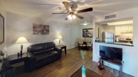 This single-floor residence offers a thoughtfully designed layout that balances comfort and functionality across its key living spaces. The living room serves as the heart of the home, featuring rich hardwood-style flooring, a ceiling fan with integrated lighting, and a sliding glass door fitted with vertical blinds that allows natural light to fill the space. The open-plan layout connects the living area seamlessly to a dedicated dining space, creating an inviting flow ideal for everyday living and entertaining. The kitchen is efficiently designed with white cabinetry, dark countertops, and a full suite of stainless steel appliances, including a refrigerator, range, and dishwasher, all set above light wood-style flooring. The bedroom is a restful retreat with hardwood-style flooring, a window with blinds for natural light control, and ample space for a dresser and full-size bed. Textured ceilings are present throughout the unit, adding a subtle design element to each room. The bathroom is clean and functional, featuring a tub-shower combination with white tile surround, a vanity with dark countertop, and wood-style flooring. Overall, the space presents a practical and comfortable living environment with consistent, coordinated finishes throughout.