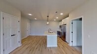 This contemporary townhouse in Elgin, IL offers 1080 square feet of living space across two floors. The property features two bedrooms, including a generous 200 square foot primary bedroom, and two full bathrooms. The main level showcases an open-concept design with a modern kitchen as its centerpiece. The kitchen boasts sleek white cabinetry, stainless steel appliances, and a large island with a built-in sink and ample seating space. A striking rectangular chandelier adds a touch of elegance to the space.

Light-toned hardwood flooring flows throughout the main living areas, while plush carpeting adds comfort to the bedrooms. Large windows in every room flood the space with natural light, creating a bright and airy atmosphere. The bathrooms feature contemporary fixtures, including floating vanities with ample storage space.

A standout feature is the in-unit laundry room, complete with full-sized, stacked washer and dryer units. The property also includes a private balcony or patio, accessible through sliding glass doors, offering outdoor living space and views of the surrounding area.

The neutral color palette, clean lines, and modern finishes throughout create a fresh and inviting ambiance, perfect for contemporary living. This townhouse combines functionality with style, making it an ideal home for those seeking a low-maintenance, high-quality living space in a suburban setting.