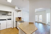 Located at 2104 Canal St in Houston's 77003 zip code, this 2-bedroom, 2-bathroom residence offers a well-designed single-floor layout that maximizes functionality and comfort. The open-concept living and dining area is anchored by warm hardwood-style flooring, a ceiling fan, and French doors that invite abundant natural light and provide views of the surrounding neighborhood. The kitchen features a peninsula with granite countertops, white cabinetry, a tile backsplash, a stainless steel sink, and a stainless steel refrigerator, flowing seamlessly into the main living space. A dedicated laundry area with a full-size washer and dryer is conveniently tucked adjacent to the kitchen. The spacious primary bedroom offers generous square footage with its own closet, while the second bedroom is carpeted and benefits from a large window with open city views and a ceiling fan. Both bathrooms are finished with wood-style flooring; one includes a tiled shower-tub combination with neutral earth-tone tile surround. Two closets provide additional storage throughout the home. The overall ambiance is clean, bright, and move-in ready, with a neutral white palette that complements the warm flooring tones throughout.