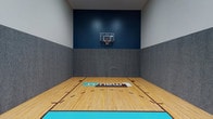 This single-floor amenity space at Renew Eden Prairie is thoughtfully designed to support both recreation and community engagement. The standout feature is a full indoor basketball court, finished with a classic hardwood-style floor marked with regulation court lines and accented with teal boundary details. The court is enclosed by gray padded walls and a bold navy blue accent wall, which frames a wall-mounted basketball hoop illuminated by overhead spotlights. The soaring ceiling height provides ample clearance for play, creating an energetic and well-appointed athletic environment.

Adjacent to the court is a generously sized community kitchen area, outfitted with rich, dark espresso cabinetry and granite-look countertops. Stainless steel appliances — including a full-size refrigerator, electric range with hood, dishwasher, and microwave — make this kitchen fully functional for events and gatherings. Light tile flooring runs throughout the kitchen and connecting corridor, complementing the neutral wall tones and drop-panel ceiling. A large window fitted with horizontal blinds allows natural light to filter in while offering views of the surrounding neighborhood. The open layout connects seamlessly between the kitchen and a flexible adjoining area, lending the space versatility for a range of community uses.