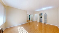 Located at 526 E Windsor Rd in Glendale, CA, this single-floor unit offers a well-organized layout comprising a living room, kitchen, bathroom, and hallway. The spacious living room is a standout feature, boasting gleaming hardwood floors that reflect abundant natural light streaming in through a front-facing window. Warm beige walls and clean white trim create a neutral, inviting palette, while a full-wall mirrored closet adds depth and further enhances the brightness of the room. The kitchen is thoughtfully appointed with gray shaker-style cabinetry offering generous storage, a white quartz countertop with an undermount sink, and a black stainless gas range. Decorative tile flooring adds visual interest and contrasts neatly with the cabinetry. A connecting hallway links the kitchen and living areas, facilitating smooth flow throughout the unit. The bathroom is clean and functional, featuring light tile flooring, a single vanity with white cabinetry, a framed mirror, and a full bathtub with a sliding frosted-glass enclosure in brushed nickel finishes. Throughout the space, the consistent use of warm neutrals, ample lighting, and practical finishes combine to create a cohesive and comfortable living environment in the heart of Glendale.