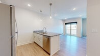 Located at 3335 N 185th Ct in Elkhorn, Nebraska, this thoughtfully designed studio unit offers a clean, modern aesthetic across its single-floor layout. The open-concept kitchen and living area serves as the heart of the space, centered around a sleek peninsula with granite countertops and an undermount sink, accented by stylish pendant lighting. The kitchen is equipped with a full suite of stainless steel appliances, including a refrigerator, range, microwave, and dishwasher, all complemented by crisp white shaker cabinetry. Light wood-style flooring flows throughout the main living area, creating a bright and cohesive feel. A large sliding glass door opens to a private balcony, flooding the living space with natural light and offering open views of the surrounding neighborhood. The bathroom features a full tub-shower combination, white cabinetry, and matching granite countertops consistent with the kitchen's finishes. A spacious walk-in closet with dual hanging rods and carpeted flooring provides generous storage. Recessed lighting and neutral wall tones throughout contribute to the unit's clean, contemporary ambiance.