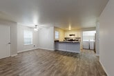 Located in Vancouver, WA, this single-floor, 2-bedroom, 2-bathroom unit offers a practical and comfortable layout designed for everyday living. The open-concept living and kitchen area is anchored by durable wood-look flooring and neutral gray walls, creating a bright, cohesive feel. A ceiling fan adds comfort to the living room, which receives natural light through multiple windows fitted with blinds. The kitchen features white cabinetry, dark granite-style countertops, a peninsula with additional prep space, and stainless steel appliances including a range and refrigerator. A dedicated in-unit laundry room with a full-size washer and dryer adds convenience. The primary bedroom is generously sized, carpeted for comfort, and includes a walk-in closet with dual hanging rods offering ample storage. The second bedroom features rich wood-look flooring and a window for natural light. Both bathrooms are finished with white vanity cabinetry, dark countertops, and tub/shower combos. Textured ceilings are consistent throughout the unit. The thoughtful layout connects all rooms via a central hallway, making efficient use of the well-proportioned floor plan.
