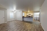 Located in Vancouver, WA, this single-floor, 2-bedroom, 2-bathroom unit offers a practical and comfortable layout designed for everyday living. The open-concept living and kitchen area is anchored by durable wood-look flooring and neutral gray walls, creating a bright, cohesive feel. A ceiling fan adds comfort to the living room, which receives natural light through multiple windows fitted with blinds. The kitchen features white cabinetry, dark granite-style countertops, a peninsula with additional prep space, and stainless steel appliances including a range and refrigerator. A dedicated in-unit laundry room with a full-size washer and dryer adds convenience. The primary bedroom is generously sized, carpeted for comfort, and includes a walk-in closet with dual hanging rods offering ample storage. The second bedroom features rich wood-look flooring and a window for natural light. Both bathrooms are finished with white vanity cabinetry, dark countertops, and tub/shower combos. Textured ceilings are consistent throughout the unit. The thoughtful layout connects all rooms via a central hallway, making efficient use of the well-proportioned floor plan.