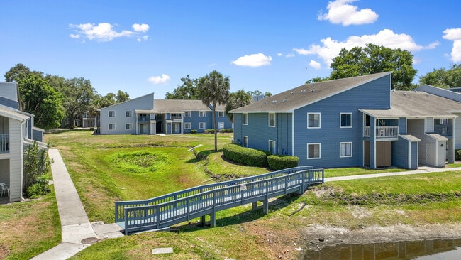 Charming blue apartment buildings with modern design, surrounded by lush greenery and scenic pathways. - Vista North