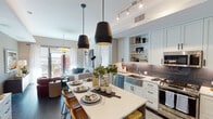 Located in the heart of downtown Phoenix at 125 E Washington St, this thoughtfully designed residence offers a seamless blend of contemporary style and urban convenience. The open-concept living and kitchen area serves as the centerpiece of the home, where crisp white shaker cabinetry, a gray tile backsplash, and a full suite of stainless steel appliances — including a gas range and French door refrigerator — create a highly functional culinary space. A large waterfall-edge island with bar seating anchors the kitchen and flows naturally into the dining area, illuminated by striking black pendant lights. The living room extends toward floor-to-ceiling sliding glass doors that open onto a private balcony, filling the space with natural light and offering views of the surrounding cityscape. Two generously sized bedrooms feature large windows with urban views, ceiling fans, and ample room for comfort. The primary bathroom is elongated and refined, with a dual-sink vanity, extensive cabinetry, large-format tile flooring, and a walk-in glass-enclosed shower. A second full bathroom mirrors the same clean aesthetic. Dark hardwood floors throughout the main living areas contrast beautifully with the light, neutral palette, lending the residence a warm yet modern ambiance throughout.