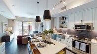 Located in the heart of downtown Phoenix at 125 E Washington St, this thoughtfully designed residence offers a seamless blend of contemporary style and urban convenience. The open-concept living and kitchen area serves as the centerpiece of the home, where crisp white shaker cabinetry, a gray tile backsplash, and a full suite of stainless steel appliances — including a gas range and French door refrigerator — create a highly functional culinary space. A large waterfall-edge island with bar seating anchors the kitchen and flows naturally into the dining area, illuminated by striking black pendant lights. The living room extends toward floor-to-ceiling sliding glass doors that open onto a private balcony, filling the space with natural light and offering views of the surrounding cityscape. Two generously sized bedrooms feature large windows with urban views, ceiling fans, and ample room for comfort. The primary bathroom is elongated and refined, with a dual-sink vanity, extensive cabinetry, large-format tile flooring, and a walk-in glass-enclosed shower. A second full bathroom mirrors the same clean aesthetic. Dark hardwood floors throughout the main living areas contrast beautifully with the light, neutral palette, lending the residence a warm yet modern ambiance throughout.