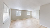 Located at 125 I-10 Service Rd in Beaumont, TX, this single-story 1-bedroom, 1-bathroom unit offers a clean, modern aesthetic throughout. Light wood-tone flooring runs seamlessly across all rooms, creating a cohesive and airy feel. The spacious living room features textured ceilings, neutral beige walls, and multiple windows dressed with blinds that allow generous natural light to fill the space. A dedicated entry door provides direct access from this area. The generously sized primary bedroom includes two windows with outdoor views of surrounding greenery, a walk-in closet with built-in rod shelving, and ample space for a full bedroom suite. The galley-style kitchen is efficiently designed with white cabinetry, stainless steel appliances including a range, microwave, dishwasher, and refrigerator, plus a single-basin sink. The full bathroom features a tub/shower combination, a white vanity with storage, and a wall-mounted mirror with overhead lighting. Neutral tones, white trim, and consistent flooring throughout contribute to a clean, move-in-ready atmosphere that is both functional and inviting.