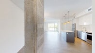 Located at 78-80 Rue Dollard-Des-Ormeaux in Gatineau, this modern 2-bedroom, 2-bathroom unit offers a bright and contemporary living experience across a single, well-organized floor. Light hardwood flooring flows throughout the main living areas, complementing the clean white walls and crisp finishes that define the space's modern aesthetic. Exposed concrete columns add an industrial touch, providing a striking contrast to the otherwise polished interior.

The open-concept living, dining, and kitchen area forms the heart of the unit, bathed in natural light from large windows that frame views of the surrounding neighbourhood. The kitchen is outfitted with sleek white cabinetry, a white tile backsplash, stainless steel appliances, and a central island — ideal for both cooking and casual dining. A stylish gold-toned chandelier anchors the dining area with a refined accent.

The spacious primary bedroom features a large window with outdoor views and generous proportions, while the second bedroom benefits from its own window and ample natural light. Both bathrooms are finished with neutral stone-look tiles; the main bathroom includes a soaking tub and a glass-enclosed shower, while the second offers a standalone glass shower. A dedicated laundry room houses stacked washer and dryer units alongside the water heater, adding practical convenience to this well-appointed home.