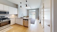 Located at 700 Bloomfield Ave in Bloomfield, CT, this thoughtfully designed one-bedroom, two-bathroom residence offers a modern living experience on a single floor. The open-concept layout seamlessly connects the kitchen and living area, creating a bright and functional space bathed in natural light from large windows with outdoor views.

The contemporary kitchen is a standout feature, boasting sleek white cabinetry, granite countertops, stainless steel appliances including a refrigerator, gas range, microwave, and dishwasher, and a central island with bar seating — ideal for casual dining or entertaining. Pendant lighting and track lighting add a stylish, modern touch, while light hardwood flooring runs throughout the main living area.

The bedroom is a comfortable retreat with soft wall-to-wall carpeting, generous natural light from a wide window overlooking the outdoors, and access to a walk-in closet with built-in shelving. The en-suite bathroom features a walk-in shower with large-format dark tile, clean white fixtures, and a modern vanity. A second full bathroom provides added convenience for guests. The overall ambiance is clean, contemporary, and move-in ready.
