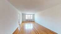 Located at 40 Barker Ave in White Plains, NY, this 2-bedroom, 1.5-bathroom residence offers a well-organized single-floor layout with consistent hardwood flooring throughout. The spacious living area is a standout feature, bathed in natural light from large multi-pane windows that overlook tree-lined surroundings. Clean white walls and polished wood floors create a bright, open ambiance that carries through every room. A second living or dining area extends the main living space, providing flexibility for various arrangements. Both bedrooms are generously proportioned, each featuring hardwood floors, windows with natural light, and closet space. Radiator heating units are present in the bedrooms, reflecting the building's classic construction. The kitchen is efficiently designed with white cabinetry, granite-style countertops, a gas range, refrigerator, and a stainless steel sink, all set above a classic checkered tile floor. The layout connects rooms through a central hallway, offering a sense of flow and privacy. With its combination of classic architectural details, abundant natural light, and hardwood flooring throughout, this White Plains residence presents a clean, move-in ready living environment.