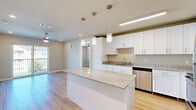 This thoughtfully designed 2-bedroom, 2-bathroom residence offers a clean, modern aesthetic throughout its single-floor layout. The open-concept kitchen serves as the heart of the home, showcasing crisp white shaker cabinetry, granite countertops, and a full suite of stainless steel appliances including a refrigerator, range, microwave, and dishwasher. A large central island with pendant lighting above provides additional prep space and casual seating, flowing seamlessly into the living area. Light-toned hardwood flooring extends throughout the entire residence, creating a cohesive and bright atmosphere. The primary bedroom is a comfortable retreat, featuring a ceiling fan, recessed lighting, dedicated closet space, and direct access to a private bathroom. The second bedroom offers similar finishes, including a ceiling fan and its own closet, with a window that invites natural light and outdoor views. Both bathrooms are finished with granite-topped white vanities, brushed nickel hardware, and wood-look tile flooring; one includes a full tub-shower combination. Two dedicated closets provide ample storage. The neutral color palette and consistent use of quality finishes throughout create a cohesive, move-in-ready living environment.
