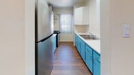 Located in the desirable Westwood neighborhood of Los Angeles, this single-story unit at 11070 Strathmore Dr offers a practical and well-organized layout throughout. The living area is generously sized, featuring warm hardwood-style flooring and a sliding glass door that opens to a private balcony, allowing natural light to fill the space and providing pleasant outdoor views of the surrounding greenery.

The galley-style kitchen is a functional standout, featuring distinctive teal cabinetry paired with white countertops, a stainless steel refrigerator, a gas range, and a double basin sink beneath upper white cabinets. A window with vertical blinds at the end of the kitchen allows additional natural light into the space.

The bedroom is carpeted and offers a built-in closet system with sliding doors and upper storage cabinets, complemented by a window overlooking mature trees. The clean, neutral tones throughout the bedroom create a calm and restful atmosphere.

The bathroom maintains a clean, white aesthetic with a vanity featuring under-sink storage, a wall mirror, and a tiled shower-tub combination. Overall, the unit presents a cohesive, functional living space in a prime Los Angeles location.