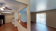 This single-floor residence in Sherman offers a functional and comfortable layout designed for everyday living. The open living area features hardwood-style flooring and a large sliding glass door fitted with vertical blinds, allowing generous natural light and outdoor views. A distinctive wood-topped pass-through bar connects the living space to the kitchen, creating an open, connected feel between the two areas. The kitchen is well-equipped with white cabinetry, speckled countertops, a double stainless steel sink, black appliances including a refrigerator and dishwasher, and hardwood-style flooring that continues the home's cohesive aesthetic. The bedrooms are carpeted and generously sized, each featuring ceiling fans with light fixtures. One bedroom includes a walk-in closet, providing ample storage, while another offers a window with outdoor views. The two bathrooms each include a full tub-shower combination with white tile surround and chrome fixtures. One bathroom features a vanity with speckled countertops and a large mirror. Throughout the home, textured ceilings and neutral wall tones create a clean, move-in ready atmosphere well-suited for a variety of living arrangements.