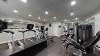 Located at 5055 Harbour Lake Drive in Goose Creek, South Carolina, this fitness center offers a well-appointed, single-floor exercise facility designed to support a wide range of workout routines. The space features durable rubber flooring throughout, providing both safety and comfort during exercise. Recessed lighting illuminates the room evenly, creating a bright and motivating environment.

The cardio section is generously equipped with multiple True-brand treadmills, elliptical trainers, and stationary recumbent bikes, allowing users to engage in a variety of cardiovascular workouts. A central strength training station anchors the space with a multi-functional cable machine, while additional equipment including a leg press, weight bench, and free weights rounds out the resistance training options.

Large wall-mounted mirrors span a significant portion of the room, enhancing the sense of space and allowing users to monitor their form during exercise. A wall-mounted television provides entertainment options, and a water dispenser is conveniently positioned for easy access. Motivational artwork and a clearly posted gym rules sign add to the functional, community-oriented atmosphere. Windows along one wall allow natural light to filter in, complementing the recessed overhead lighting. A dedicated exit door ensures convenient and safe access to and from the facility.