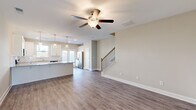 This well-appointed two-story home at 268 Dolcetto Drive in Winder, Georgia offers three bedrooms and three bathrooms across two thoughtfully designed floors. The main level sets a welcoming tone with a wide entrance hallway that opens into a bright, open-concept living and kitchen area. Durable wood-look luxury vinyl plank flooring runs throughout the main floor, complemented by neutral warm-gray walls and crisp white trim. The living room features a ceiling fan and flows seamlessly toward the staircase, which is accented by a stylish black metal baluster railing. The kitchen stands out with white shaker-style cabinetry, granite countertops, a subway tile backsplash, stainless steel appliances including a French door refrigerator and dishwasher, and pendant lighting above the peninsula. The upper floor hosts all three bedrooms, each equipped with ceiling fans and plush carpet flooring. The generously sized primary bedroom includes a walk-in closet with wire shelving. The bathrooms are finished with white vanities and tub-shower combinations. A dedicated laundry room on the upper level houses a Whirlpool front-load washer and dryer. Natural light fills the bedrooms through double windows with views of the surrounding neighborhood.
