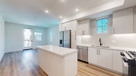 Located at 1205 Aviara Parkway in Carlsbad, CA, this thoughtfully designed one-bedroom, one-bathroom residence offers a clean, modern aesthetic across a single floor. The open-concept kitchen and living area serves as the heart of the home, featuring sleek white flat-panel cabinetry, a white quartz center island, stainless steel appliances including a French door refrigerator, gas range, microwave, and dishwasher, complemented by a white subway tile backsplash. Recessed lighting illuminates the space, while multiple windows allow generous natural light to flow through. Light wood-tone luxury vinyl plank flooring runs consistently throughout, lending warmth and visual continuity to every room. The living area opens to a private balcony, extending the functional living space outdoors with views of the surrounding Carlsbad community. The bedroom offers a comfortable footprint with dual windows framing neighborhood views, white walls, and the same wood-tone flooring. The bathroom is finished with a full soaking tub and shower combo adorned with white tile surround, matte black fixtures, a vanity with storage, and light-toned tile flooring. A dedicated closet and hallway complete the efficient, well-planned layout of this contemporary Carlsbad residence.