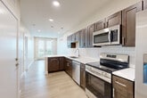 Located at 130 N 39th St in Omaha, Nebraska, this well-appointed one-bedroom, one-bathroom unit offers a thoughtfully designed layout across a single level. The open-concept kitchen is a standout feature, boasting rich dark-brown shaker cabinetry, crisp white quartz countertops, a classic subway tile backsplash, and a full suite of stainless steel appliances including a range, microwave, dishwasher, and refrigerator. Light wood-style flooring runs throughout the main living and kitchen areas, contributing to a clean, contemporary aesthetic. Recessed lighting and pendant fixtures provide warm, even illumination throughout. The kitchen flows naturally toward the living area and a glass-paneled door that fills the space with natural light and outdoor views. The bedroom is a comfortable retreat finished with plush carpeting, a ceiling fan, and a large window that invites ample natural light. A dedicated closet offers convenient storage. The full bathroom features dark cabinetry with quartz countertops, wood-look tile flooring, and a tub-shower combination. Clean neutral tones and modern brushed nickel hardware unify the space, creating a cohesive and move-in-ready home with a polished, modern feel.