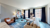 Located at 205 S High St in the heart of downtown Columbus, Ohio, this thoughtfully designed single-floor residence blends modern aesthetics with urban convenience. The open-concept layout allows for seamless flow between the living, dining, and kitchen areas, all anchored by warm hardwood-style flooring throughout.

The living room is a standout space, featuring large grid-pane windows dressed with navy curtains and gold hardware that frame views of the surrounding cityscape. The room is bright and welcoming, with generous wall space showcasing bold artwork that adds a vibrant, contemporary character.

The kitchen is well-appointed with white shaker cabinetry, granite countertops, a full suite of stainless steel appliances, a tiled backsplash, and a center island with bar seating. Rustic open shelving along one wall adds both style and functionality.

The bedroom is serene and elegantly finished, with soft gray tones, a recessed headboard niche, and a window that draws in natural light. The calm color palette and refined details create a restful retreat.

The bathroom features a soaking tub with subway tile surround, a wide vanity with white cabinetry, and open wood shelving for storage. Clean lines and neutral tones give the space a polished, spa-like feel. Overall, the residence offers a refined and comfortable urban living experience.