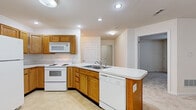 Located at 8555 Alexandra Drive in North Royalton, Ohio, this two-bedroom, one-bathroom residence offers a practical and comfortable single-floor layout. The kitchen is a standout feature, equipped with warm oak cabinetry, white appliances including a refrigerator, electric range, built-in microwave, and dishwasher. A peninsula counter with a double stainless steel sink adds both functionality and a natural divide between the kitchen and the adjoining dining area, which is accented by an elegant chandelier overhead. The living room is bright and welcoming, with neutral-toned carpet, a glass-panel exterior door, and two windows that bring in ample natural light. The primary bedroom is generously sized, featuring plush carpeting, dual closet doors flanking a window, and a clean, neutral palette. The second bedroom also offers carpeted flooring and a window with outdoor views, providing a comfortable and quiet space. The bathroom is cleanly appointed with an oak vanity, a large mirror, and a sliding glass door shower enclosure. Throughout the residence, consistent light-toned walls and carpeting create a cohesive, understated ambiance well-suited for everyday living.