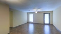 Located at 111 Lakeshore Dr in Brandon, Mississippi, this single-floor property offers a clean, functional layout with a comfortable and practical design throughout. The main living area is a standout feature, showcasing rich hardwood-style flooring that extends across the open space, complemented by neutral-toned walls that create a bright and welcoming atmosphere. A ceiling fan with a light fixture is centrally mounted, providing both airflow and ambient lighting. The textured ceiling adds a classic residential touch. Natural light flows generously into the room through multiple windows fitted with horizontal blinds, allowing for easy light control. A glass-paneled door provides additional brightness and potential access to an outdoor area. The baseboards and trim are finished in a contrasting dark tone that ties together the flooring and wall palette cohesively. The overall ambiance of the space is understated and move-in ready, offering a neutral canvas well-suited for a variety of interior styles. Situated in the Brandon, MS area, the property benefits from a suburban setting with convenient access to local amenities.