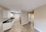 This single-floor, 2-bedroom, 1-bathroom home offers a practical and straightforward layout designed to maximize every square foot of its compact footprint. Light beige walls and large neutral-toned tile flooring run consistently throughout the space, creating a cohesive and easy-to-maintain interior.

The galley-style kitchen is well-equipped, featuring white cabinetry with ample upper and lower storage, dark granite-style countertops, a double stainless steel sink, a stainless steel refrigerator, and a range — all arranged efficiently along parallel walls. A dedicated dining area sits adjacent to the kitchen, offering a natural flow for everyday living. The living room provides an open, flexible space with tile flooring and access to the rest of the home via a central hallway.

Both bedrooms are comfortably sized with the same tile flooring and neutral walls. The primary bedroom is notably spacious and includes a closet, while the second bedroom features a window that allows in natural light and its own closet. A third closet provides additional storage elsewhere in the home.

The bathroom includes a walk-in tiled shower with a mosaic tile floor, a toilet, and a vanity mirror with storage — practical and clean in design. With three closets distributed throughout, storage is well accounted for in this efficiently organized home.