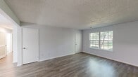 Located at 1932 Garland Sq in Manchester, NJ, this single-floor, 2-bedroom, 1-bathroom home offers a clean and functional layout with consistent hardwood-style flooring throughout. The living room is a welcoming, open space filled with natural light streaming through large multi-pane windows that frame views of the surrounding greenery, complemented by a textured ceiling and neutral gray walls. The well-appointed kitchen features white cabinetry, granite-look countertops, a stainless steel refrigerator, and a stainless steel range, all set atop light-toned hardwood-style flooring. A hallway connects the main living areas to the bedrooms and bathroom. The spacious primary bedroom includes a wide closet with sliding doors and a large window overlooking the outdoors, while the second bedroom is a comfortable, well-lit room with ample wall space. An additional walk-in closet with wire shelving provides generous storage. The bathroom is neatly finished with a white vanity, medicine cabinet with mirrored doors, and a lighted fixture above. A utility room completes the layout. Throughout the home, the light, neutral color palette and consistent flooring create a cohesive and move-in-ready atmosphere.