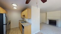 Located at 4620 South 254th Place in Kent, Washington, this single-floor residence offers a well-organized layout designed for comfortable everyday living. The galley-style kitchen is efficiently arranged with light maple cabinetry providing ample storage, laminate countertops, a stainless steel sink, a dishwasher, a range, and a full-size refrigerator. Tile flooring runs throughout the kitchen, adding durability and ease of maintenance. A ceiling fan positioned at the kitchen's edge serves the adjacent living area, which features a fireplace as a central focal point and is finished with plush carpeting. The bedrooms are carpeted and receive natural light through windows that offer views of the surrounding neighborhood. The bathroom is finished with tile flooring and includes a full tub-shower combination, toilet, and bright white fixtures in a clean, functional layout. The overall interior palette is neutral throughout, with warm beige tones on the walls and white trim, creating a bright and cohesive ambiance. The floor plan, as seen in the dollhouse view, reflects a straightforward and practical layout that maximizes the use of interior space across a single level.