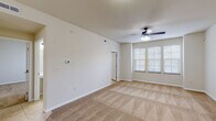 This single-floor residence offers a practical and comfortable layout designed for easy living. The main living area is generously sized, featuring warm beige carpeting, neutral-toned walls, and a ceiling fan with integrated lighting. Multiple windows allow natural light to fill the space, creating a bright and welcoming atmosphere. The transition between the living area and kitchen is marked by a shift to light ceramic tile flooring, providing a clean visual distinction between the two zones.

The kitchen is efficiently designed with ample white cabinetry, granite-style countertops, and a full suite of white appliances including a refrigerator, electric range, and microwave. A peninsula with a built-in sink and pendant lighting above adds both function and style, making it an ideal space for meal preparation and casual dining.

The bedrooms continue the carpeted aesthetic, each featuring a ceiling fan, neutral walls, and windows with blinds that offer privacy while still admitting natural light. The bathroom is finished with light tile flooring, a single-sink vanity with granite-style countertops, a large mirror, and a walk-in shower enclosed with sliding glass doors. Throughout the unit, clean lines and a consistent neutral palette create a cohesive, move-in ready environment.