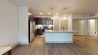 This thoughtfully designed one-bedroom, one-bathroom unit offers a clean, modern aesthetic across a comfortable single-story layout. The open-concept living area features wood-style plank flooring, neutral walls, and a ceiling fan, with a set of glass doors that invite natural light and provide outdoor views, enhancing the unit's airy ambiance.

The kitchen is a standout feature, showcasing dark espresso cabinetry extending to the ceiling, granite countertops, a classic subway tile backsplash with under-cabinet lighting, and a full suite of stainless steel appliances. A large center island with pendant lighting and an integrated sink serves as both a prep space and a natural gathering point, seamlessly connecting the kitchen to the living area.

The bedroom is carpeted for comfort, with two windows fitted with blinds that allow ample natural light while maintaining privacy. A ceiling fan adds functionality to the space. The bathroom features a dual-sink vanity with granite countertops, dark cabinetry, and a full-width mirror illuminated by modern sconce lighting, creating a polished and practical space. Hardwood-style flooring continues into the bathroom, tying the unit together cohesively.