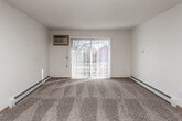 This single-floor unit offers a practical and comfortable layout across several well-defined living spaces. The living room serves as the central gathering area, featuring neutral-toned carpet, a textured ceiling, and a full-length sliding glass door dressed with vertical blinds that floods the room with natural light and provides outdoor access. A baseboard heating unit runs along the wall, ensuring year-round comfort, while a wall-mounted air conditioning unit offers additional climate control.

The kitchen is equipped with light oak cabinetry, dark laminate countertops, and a full suite of black appliances including a refrigerator, electric range, built-in microwave, and dishwasher. Stone-look tile flooring and a ceiling fan with integrated lighting complete the space, which also benefits from a dedicated closet just off the main corridor.

The bedroom is generously sized, featuring the same neutral carpet as the living area, a wall-mounted air conditioning unit, a bright window overlooking outdoor greenery, and a baseboard heater. A textured ceiling and flush-mount light fixture add to the room's functional character.

The bathroom includes a single-sink vanity with dark countertops and oak cabinetry, a large mirror, tile flooring, a baseboard heater, and a shower-tub combination, providing all essential amenities in a clean, straightforward layout.