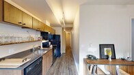 Located at 7227 N Philadelphia Ave in Portland, Oregon, this thoughtfully designed one-bedroom, one-bathroom unit offers a smart and functional single-floor layout. Hardwood-style flooring flows throughout, creating a cohesive and clean aesthetic from entry to bedroom.

The entrance leads into a well-organized corridor that connects all areas of the unit. The galley-style kitchen and living room share an open layout, with the kitchen featuring warm wood cabinetry, dark countertops, a full suite of black appliances including a range, dishwasher, refrigerator, and microwave, plus an open display shelf and stainless steel sink. Track lighting illuminates the kitchen efficiently. The adjacent living area provides a comfortable space for everyday use.

The bedroom is a cozy, well-proportioned room equipped with a ceiling fan and light fixture. Neutral walls and adequate space allow for practical furniture arrangement, and a dedicated closet adds essential storage.

The bathroom is finished with a wood-toned vanity, dark stone-style countertop, a large mirror, and a shower/tub combination. Concrete-style flooring and grab bars lend a clean, functional character to the space.

A dedicated laundry area rounds out the unit's practical amenities, making this a fully self-contained residence in Portland's St. Johns neighborhood.