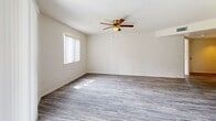 This single-floor residence offers a clean, functional layout across several well-defined living spaces. The main living area features durable wood-style plank flooring in a cool gray tone, a textured ceiling, and a ceiling fan with integrated lighting. Natural light enters through a window fitted with vertical blinds, creating a bright and open atmosphere.

The kitchen is accessed via a pass-through opening framed by shiplap-style paneling, adding a contemporary farmhouse detail. It features granite-look countertops, light cabinetry, under-cabinet lighting, and standard appliances, making efficient use of the available space.

The bedrooms are carpeted in neutral tones and each includes a ceiling fan, windows with vertical blinds for natural light control, and generous closet space. One bedroom features a bifold-door closet with a hanging rod, while additional rooms offer comparable storage solutions.

Two full bathrooms serve the unit, each finished with wood-style plank flooring, a tub and shower combination with white tile surround, chrome fixtures, and windows fitted with vertical blinds to allow natural light while maintaining privacy. The overall palette throughout is neutral white and beige, lending the space a clean, move-in-ready appearance.