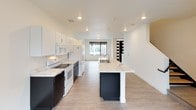 This well-appointed 4-bedroom, 2-bathroom residence spans three floors, offering generous living space designed with a clean, contemporary aesthetic. Light-toned luxury vinyl plank flooring runs throughout, complementing the bright white walls and creating a cohesive, modern feel across every level. The kitchen serves as a central highlight, featuring a large island with striking marble-style countertops, a double sink, recessed lighting, and a bold contrast between dark lower cabinetry and crisp white upper cabinets. White appliances, including a range, microwave, dishwasher, and refrigerator, complete the functional layout, which opens toward a windowed living area for a seamless flow. The bedrooms are well-sized, each with large windows that invite natural light and offer views of the surrounding neighborhood. Bold black interior doors add a modern design accent throughout. The bathrooms are thoughtfully designed, each featuring dual dark-cabinet vanities topped with marble-style countertops, flanking a separate water closet for added privacy. At least one bedroom includes a walk-in closet with wire shelving systems for organized storage. The overall ambiance is clean, modern, and move-in ready, with consistent finishes that lend a cohesive character to the entire home.