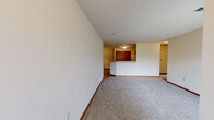 Located in New Berlin, Wisconsin, this single-floor, two-bedroom, one-bathroom residence offers a practical and comfortable layout. The open living area is finished with plush carpeting and neutral walls, creating a bright and welcoming atmosphere. A sliding glass door allows natural light to fill the space and provides access to the outdoors. The kitchen is well-equipped with warm-toned wooden cabinetry, a full suite of white appliances including a refrigerator, electric range, and microwave, and is complemented by a peninsula breakfast bar that connects seamlessly to the living area. Light wood-style flooring runs throughout the kitchen, adding a clean contrast. The primary bedroom is generously sized and includes access to two closets — one of which is a walk-in closet outfitted with wire shelving and hanging rods for ample storage. The full bathroom features a single-sink vanity with wooden cabinetry, a toilet, and a glass-door shower/tub combination, all finished with durable wood-look flooring. Warm wood-toned door trim and baseboards throughout the home add a cohesive, classic touch to the overall design.