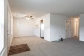 Located at 401 Jester Ct in Newport News, Virginia, this single-floor residence offers a clean, neutral aesthetic throughout. The layout, as revealed by the dollhouse view, includes a spacious living area, kitchen, multiple bedrooms, and two full bathrooms.

The living area is generously sized, featuring soft beige carpet, a ceiling fan with light fixture, and an open pass-through to the kitchen. Multiple windows allow natural light to fill the space, creating a bright and welcoming atmosphere. Built-in shelving adds a functional architectural detail to the living room wall.

The kitchen is equipped with white cabinetry featuring wood-tone trim, a coil-element electric range, a dishwasher, and a single-basin sink. Wood-look flooring and a window over the counter contribute to a practical yet pleasant workspace.

The bedrooms are well-proportioned, each finished with neutral carpet, white walls, and windows that bring in natural light and neighborhood views. The rooms offer a versatile, move-in-ready canvas.

Two full bathrooms serve the home, both featuring tub/shower combinations and wood-look flooring. One bathroom is notably equipped with grab bars and accessibility hardware, making the space suitable for a range of needs. Both bathrooms maintain a clean, functional design throughout.