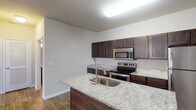 Located at 170 Cycle Dr in Boiling Springs, SC, this single-floor residence offers a well-designed layout with modern finishes throughout. The kitchen serves as a central highlight, featuring rich dark cabinetry, light granite countertops, and a suite of stainless steel appliances including a refrigerator, electric range, and over-the-range microwave. A kitchen island with an integrated sink and matching granite surface provides additional workspace and a natural gathering point that opens to the living area. Hardwood-style flooring flows through the main living spaces, lending warmth and continuity to the open-concept design. The living area is generously proportioned, offering flexible furniture arrangement options, and is enhanced by a ceiling fan and a window that allows natural light to fill the room. The bedrooms are finished with plush carpeting and ceiling fans, creating a comfortable retreat. Each bedroom provides access to a walk-in closet with wire shelving for organized storage. The bathroom includes a full tub-shower combination and hardwood-style flooring, complementing the clean, neutral palette carried throughout the home. Crisp white doors, consistent trim work, and neutral wall tones give the entire space a cohesive and move-in-ready aesthetic.