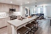 Located at 17600 Cartwright Rd in Irvine, California, this modern single-floor residence offers a thoughtfully designed open-concept layout with contemporary finishes throughout. The kitchen is a standout feature, equipped with stainless steel appliances including a gas range and microwave, light wood cabinetry, a mosaic tile backsplash, and a spacious island with bar seating — seamlessly connecting to the dining and living areas. The living room is bright and welcoming, with large windows allowing natural light to fill the space, wood-look flooring, and a stylish chandelier as a focal point. A dedicated study room features a built-in dual workstation with open shelving, ample task lighting, and generous window views, making it ideal for a home office. The primary bedroom is generously proportioned, highlighted by a gold geometric chandelier and windows that overlook the surrounding area. The primary bathroom offers a dual-sink vanity with a tiled backsplash, a large mirror, and a glass-enclosed shower. A secondary bathroom includes a full tub-shower combination and a single-sink vanity with light wood cabinetry. Wood-look flooring runs consistently throughout the unit, tying together the clean, modern aesthetic of this well-appointed Irvine residence.