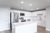 Located at 185 N West Temple in Salt Lake City, UT, this thoughtfully designed 3-bedroom, 2-bathroom residence offers a clean, modern aesthetic throughout its single-floor layout. The open-concept kitchen and living area serves as the heart of the home, anchored by a large central island with white quartz countertops, shaker-style white cabinetry, a classic subway tile backsplash, and a full suite of stainless steel appliances including a refrigerator, electric range, over-the-range microwave, and dishwasher. Light oak-toned hardwood flooring flows seamlessly throughout the entire space, enhancing the bright and airy atmosphere created by recessed lighting. The living area is bathed in natural light through expansive floor-to-ceiling sliding glass doors that open to a private balcony showcasing striking views of the Salt Lake City skyline. Each of the three bedrooms offers a comfortable, well-proportioned layout with large windows framing views of the surrounding cityscape and neighborhood. The primary bedroom includes a spacious double-door closet. Both bathrooms are finished in a crisp, contemporary style with white vanities, quartz countertops, backlit mirrors, and light hardwood flooring. The full bathroom features a tub-shower combination with subway tile surround and brushed nickel fixtures throughout.
