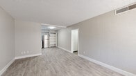 This well-maintained single-floor unit offers a bright, open layout finished with light gray hardwood-style flooring and neutral-toned walls throughout, creating a clean and cohesive aesthetic. The spacious living and dining area provides ample room for various furniture arrangements, with a textured ceiling and crisp white baseboards adding to the polished look. Built-in open shelving offers convenient storage and display space, while a separate closeted area adds to the unit's organizational functionality.

The kitchen is thoughtfully designed with white shaker-style cabinetry, light speckled countertops, and a gray subway tile backsplash. Stainless steel appliances — including a refrigerator, electric range, and dishwasher — complete the space with a modern touch. A stainless steel sink with a contemporary faucet rounds out the functional kitchen layout.

Two bedrooms feature the same light flooring, neutral walls, and textured ceilings, each with a window fitted with horizontal blinds that allow for natural light and privacy. The full bathroom includes a vanity with a speckled countertop, white cabinetry, a framed mirror, and a combined shower-tub enclosure. The unit's consistent finishes and clean design make it a practical and comfortable living space.