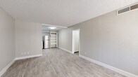 This well-maintained single-floor unit offers a bright, open layout finished with light gray hardwood-style flooring and neutral-toned walls throughout, creating a clean and cohesive aesthetic. The spacious living and dining area provides ample room for various furniture arrangements, with a textured ceiling and crisp white baseboards adding to the polished look. Built-in open shelving offers convenient storage and display space, while a separate closeted area adds to the unit's organizational functionality.

The kitchen is thoughtfully designed with white shaker-style cabinetry, light speckled countertops, and a gray subway tile backsplash. Stainless steel appliances — including a refrigerator, electric range, and dishwasher — complete the space with a modern touch. A stainless steel sink with a contemporary faucet rounds out the functional kitchen layout.

Two bedrooms feature the same light flooring, neutral walls, and textured ceilings, each with a window fitted with horizontal blinds that allow for natural light and privacy. The full bathroom includes a vanity with a speckled countertop, white cabinetry, a framed mirror, and a combined shower-tub enclosure. The unit's consistent finishes and clean design make it a practical and comfortable living space.