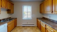 Located at 1523 N Winton Rd in Rochester, NY, this single-floor unit offers a practical and comfortable layout across several well-defined living spaces. The living area greets you with rich hardwood-style flooring, neutral walls, and a baseboard heating system, creating a warm and welcoming atmosphere. A front entry door with dual locks provides secure access directly into this open space.

The kitchen is functional and well-appointed, featuring warm honey-toned wood cabinetry on both sides, dark granite-style countertops, tile flooring, and a window fitted with horizontal blinds that brings in natural light. A baseboard heater beneath the window and standard appliances including a range and refrigerator complete the space.

The bedrooms are finished with plush wall-to-wall carpeting and neutral paint, offering a quiet and comfortable retreat. At least one bedroom benefits from a window with outdoor views and baseboard heating. Textured ceilings are consistent throughout the carpeted rooms.

The full bathroom is clean and bright, featuring white tile wainscoting, tiled flooring, a bathtub, and a window that allows natural light to filter in. A vanity and overhead lighting round out the well-maintained space. Overall, the unit presents a straightforward, move-in-ready layout suited for comfortable everyday living.